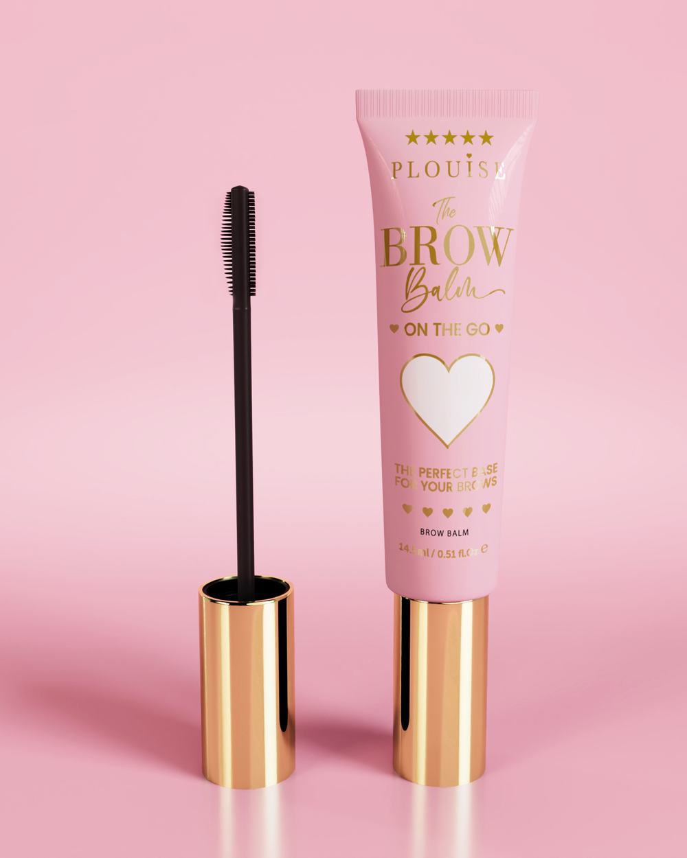 P.Louise Fluffy Soap Brow Balm Instant Fix produkt v růžové tubě se zlatým uzávěrem, doplněný černým kartáčkem na obočí, zobrazený na růžovém pozadí.