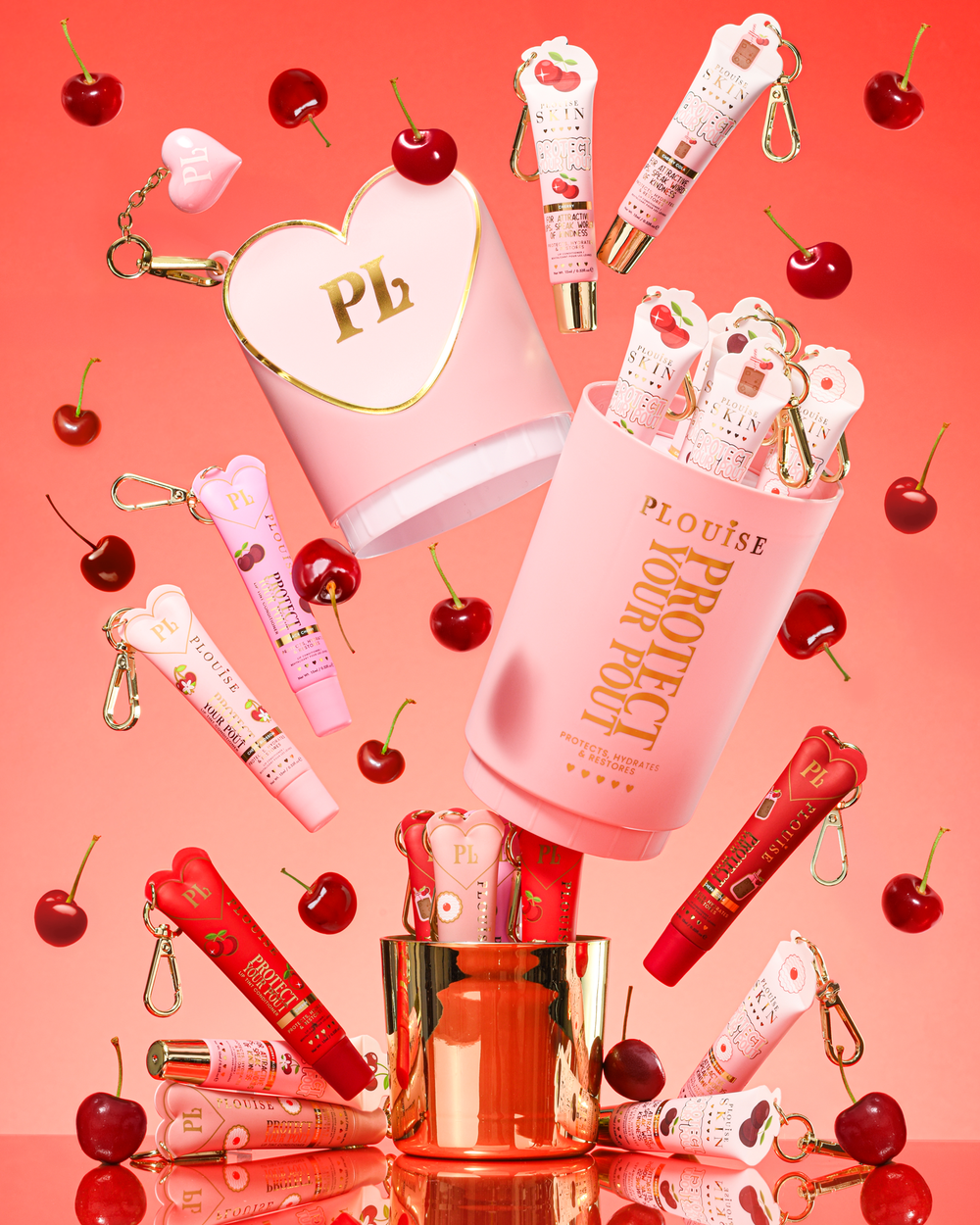 Dárková sada Pink XL Protect Your Pout, která se otevírá obklopená třešněmi a růžovými a červenými kondicionéry na rty na růžovém pozadí
