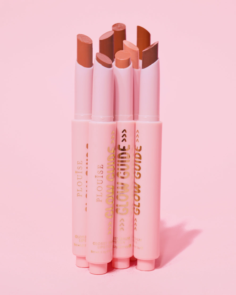 Záběr ukazující P.Louise Glow Guide Glossy Lipstick Balsm v plném rozsahu bez rtů ukazující škálu barev na růžovém pozadí
