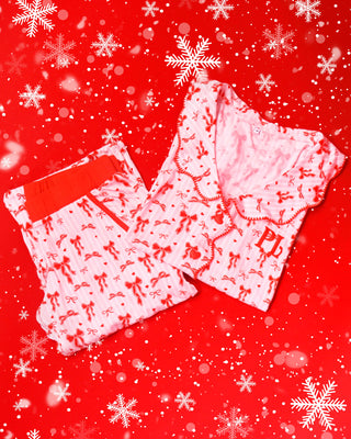 Pár růžového a bílého pruhovaného pyžama s červenými slavnostními vzory na červeném pozadí se sněhovými vločkami