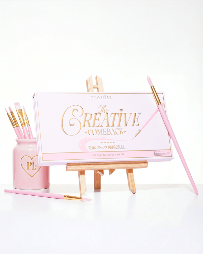 Uzavřená růžová paleta P.Louise Creative Comeback XXXL Rainbow Eyeshadow Palette umístěná na uměleckém stojanu obklopená štětci na make-up
