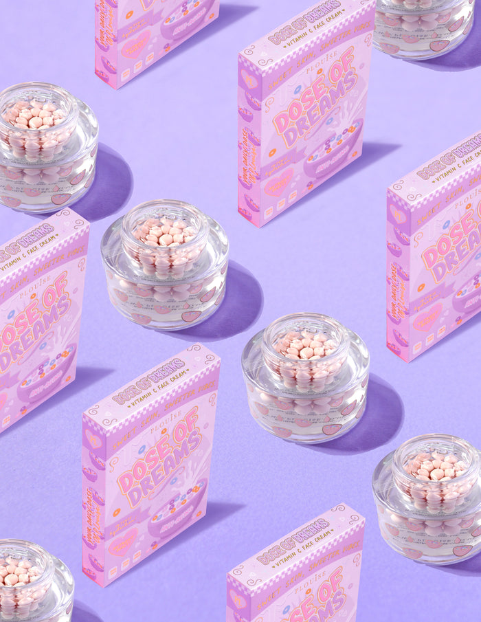 Průhledné nádobky P.Louise DOse of Dreams Viatmin C Capsule Face Cream s růžovými kapslemi v nich obklopenými růžovými cereáliemi na fialovém pozadí