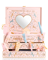 A P.Louise pastelově růžová, modrá a žlutá vánoční dárková krabička PR krásy s označením 'Your Enchanted Tale' se zrcátkem ve tvaru srdce na víku a otevřenými zásuvkami, obklopenými různými kosmetickými tubami, lahvičkami a malým váčkem na bílém pozadí.