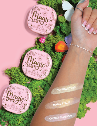 Tři kompaktní volné zvýrazňovače s označením Magic Dust v odstínech Twinkle Toes, Magic Peach a Cherry Blossom zobrazené na paži s květinovým pozadím.