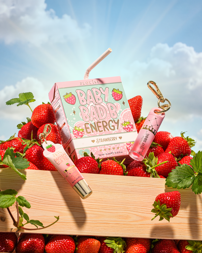 P.Louise Strawberry Baby Bad B Mini Lip Oil a Mini Lip Conditioner na stole obklopeném jahodami