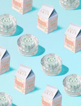 Průhledné nádobky P.Louise Dose of Dreams Vitamin C Capsule Cream s modrou kapslí uvnitř obklopené krabicemi od mléka
