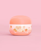 Jar of P. Louise Slick It To Me Peach Melting Body Balm s růžovým pozadím