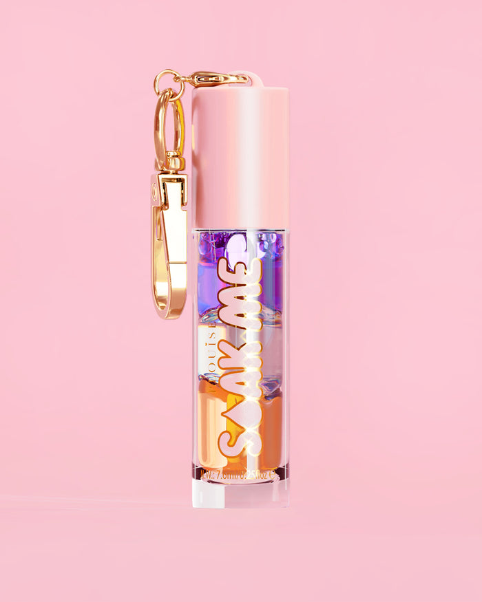 P. Louise Soak Me Lip Oil s barevným vrstveným olejem v růžové tubě se zlatou sponou na růžovém pozadí