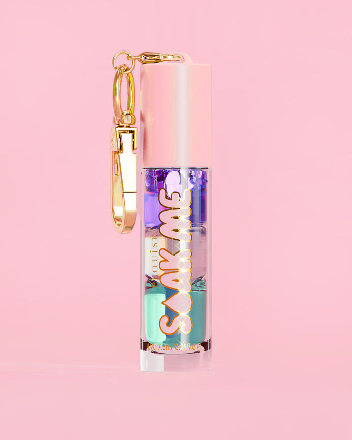 P. Louise Soak Me Lip Oil s barevným vrstveným olejem v růžové tubě se zlatou sponou na růžovém pozadí