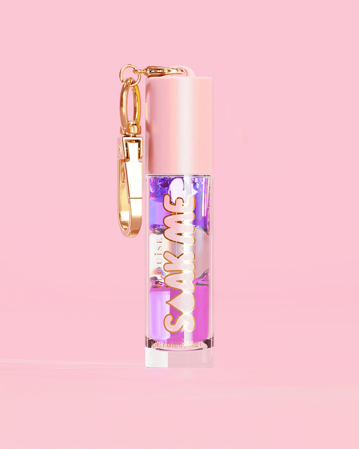 P. Louise Soak Me Lip Oil s barevným vrstveným olejem v růžové tubě se zlatou sponou na růžovém pozadí