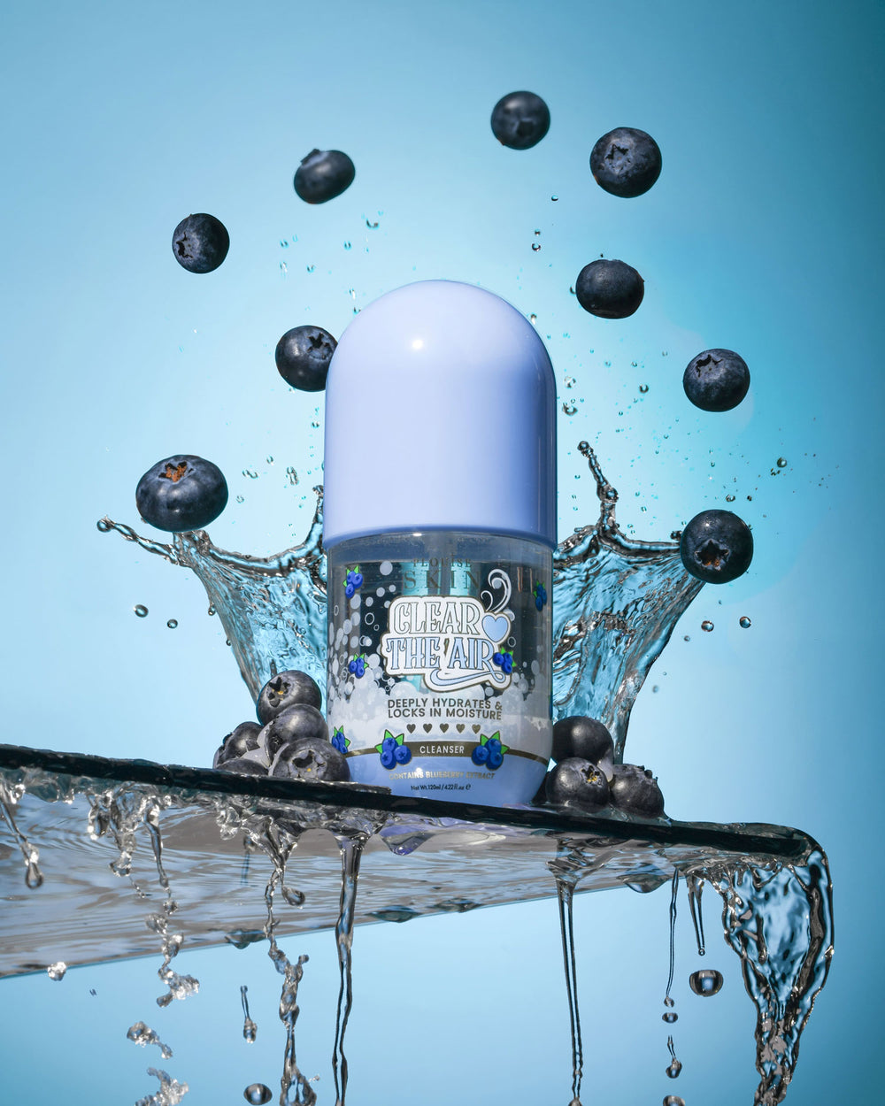 Láhev P. Louise Clear The Air Blueberry Gel Cleanserl obklopená borůvkami a stříkající vodou na modrém pozadí