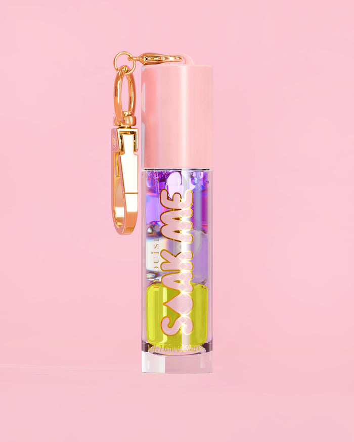 P. Louise Soak Me Lip Oil s barevným vrstveným olejem v růžové tubě se zlatou sponou na růžovém pozadí