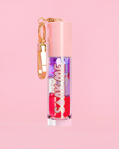 P. Louise Soak Me Lip Oil s barevným vrstveným olejem v růžové tubě se zlatou sponou na růžovém pozadí