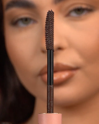 Close-up of a P.Louise Tearproof waterproof mascara wand held in front of a blurred face